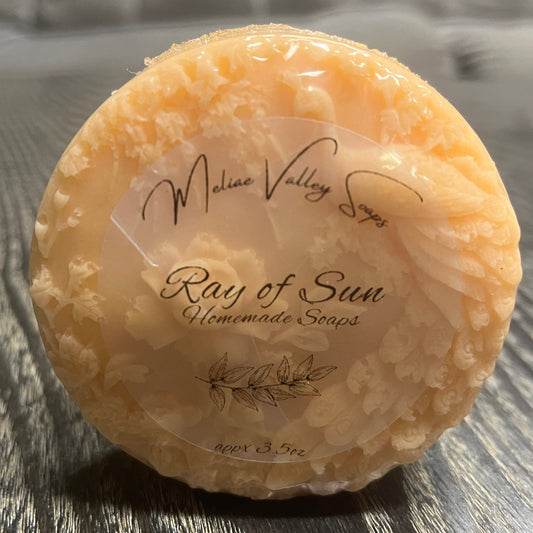 Round orange bar of soap with a label on a wooden surface.