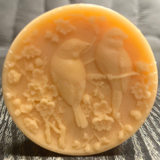 Round orange bar of soap on a wooden surface.