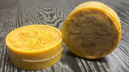 Two yellow soap bars, one with a clear label, on a wooden surface. 