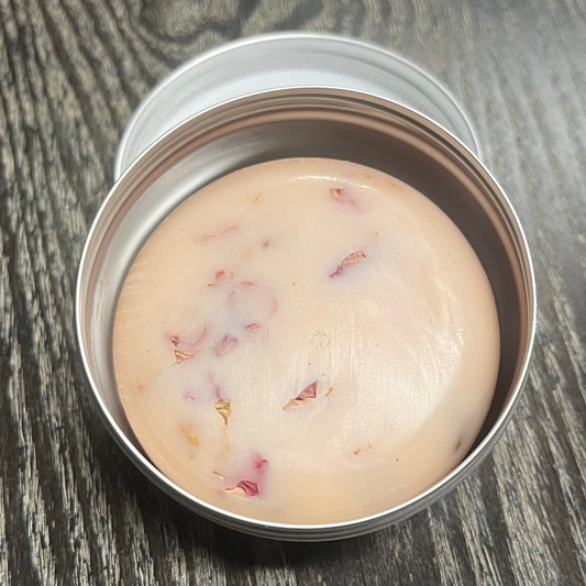 A pink lotion bar with visible rose petals in a tin.