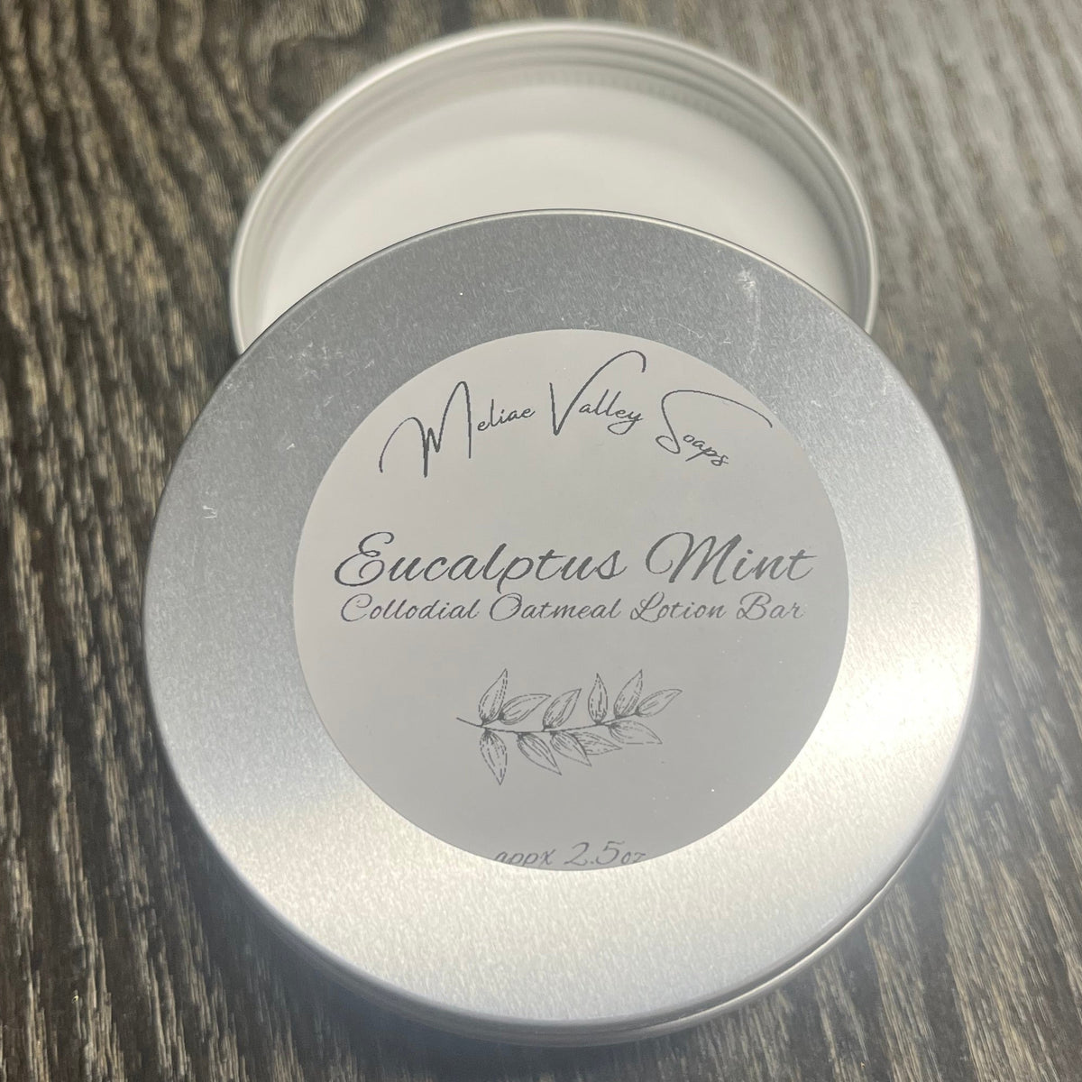 Colloidal Oatmeal lotion bar tin with label on a textured surface