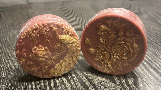 Two red bars of soap with gold mica painting on the designs. 