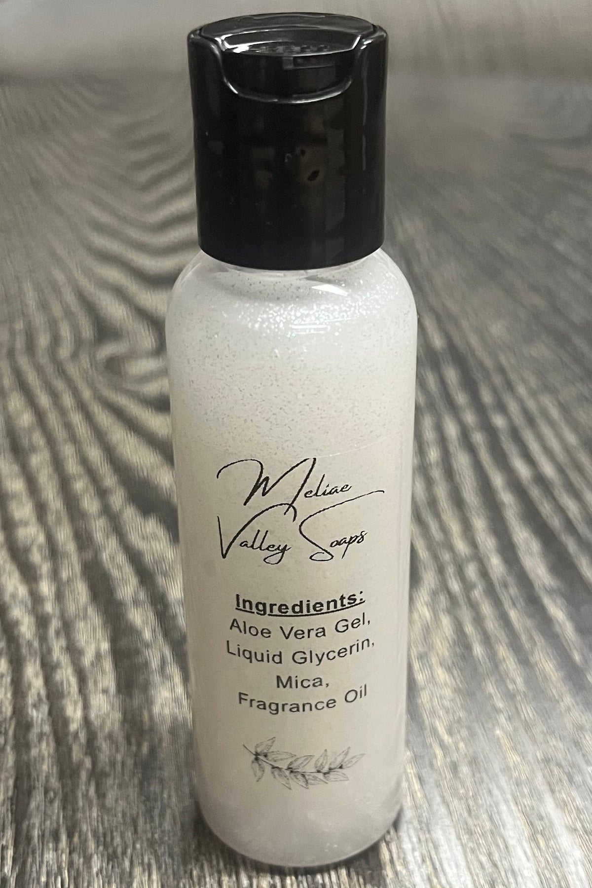 A small bottle of silver body shimmer with a clear ingredients label.