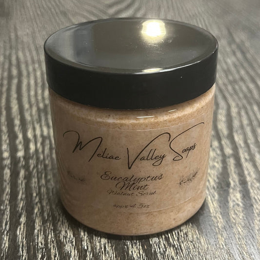 Jar of light brown walnut body scrub with a black lid and a clear label on the front.