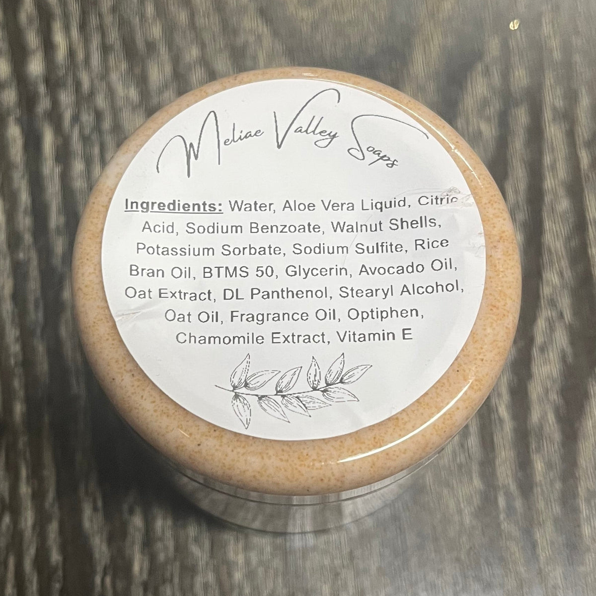 Jar of light brown walnut body scrub with a white ingredients label. 