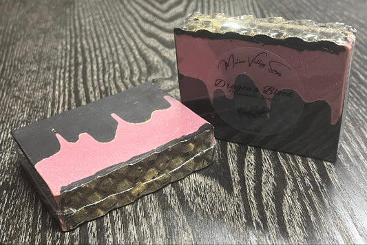 Two rectangular bars of soap with a black bottom layer and a red layer made to look like blood. A thin black top layer is textured to look like gold dragon scales.