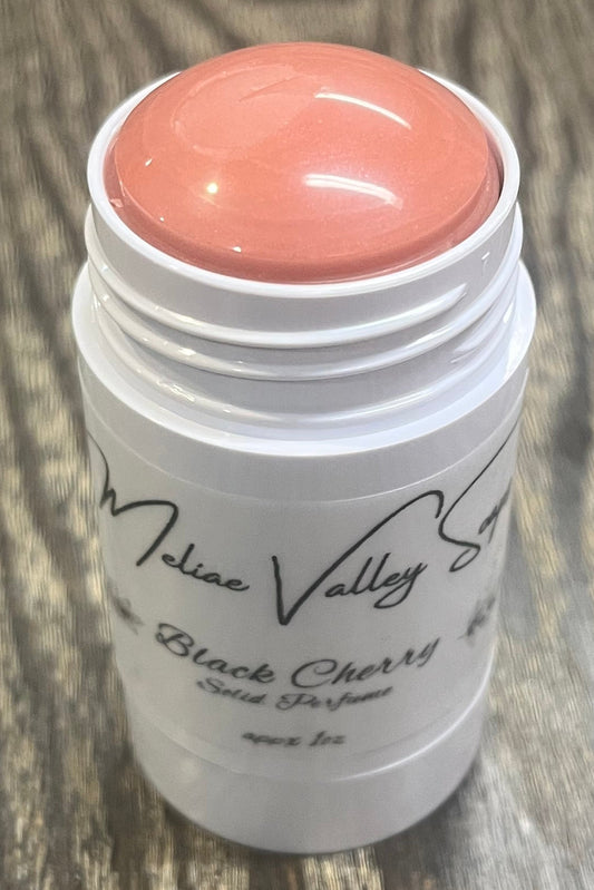 A white tube with a label on the front. The tube it open to show a red balm. 