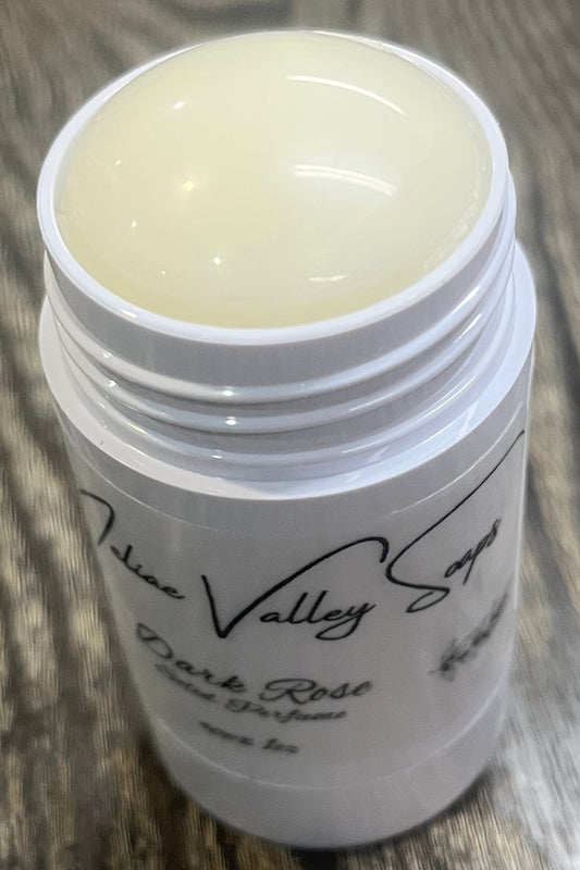 A white tube with a label on the front. The tube it open to show a beige balm. 