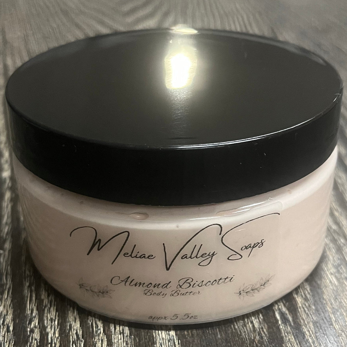Jar of light brown whipped body butter with a black lid and a clear label on the front. 