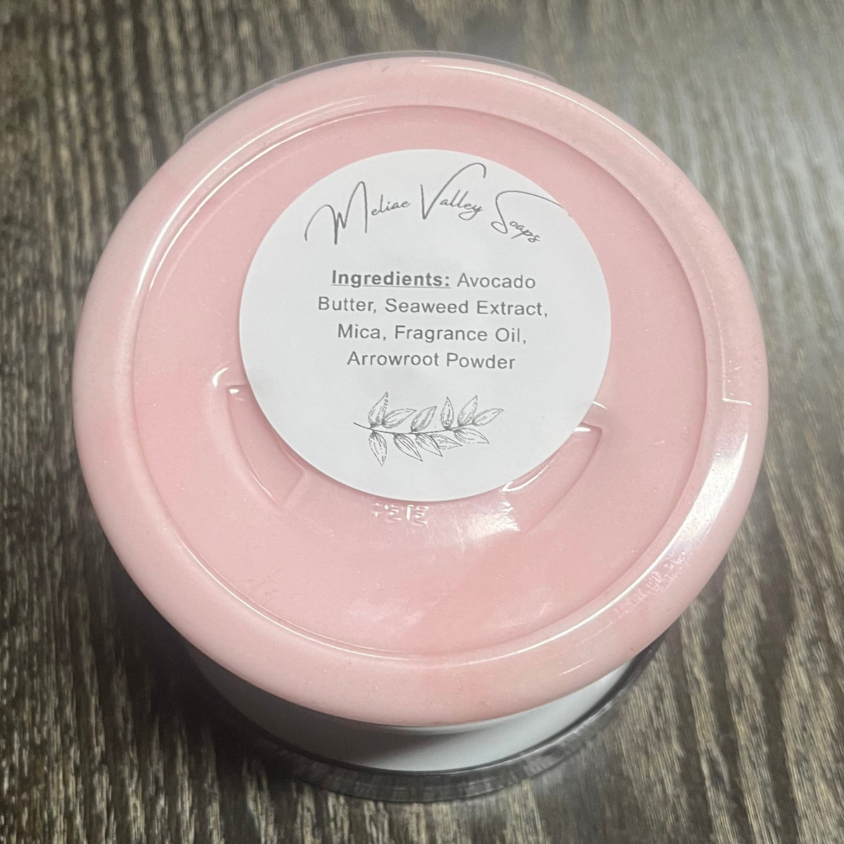 Jar of pink whipped body butter with a white ingredients label. 