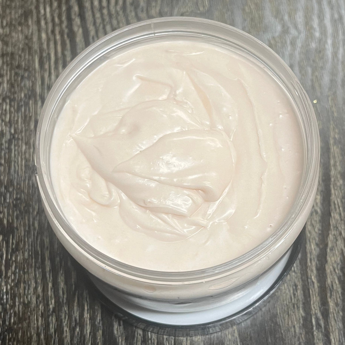 Jar of light brown whipped body butter. You can slightly see a clear label on the front from this angle. 