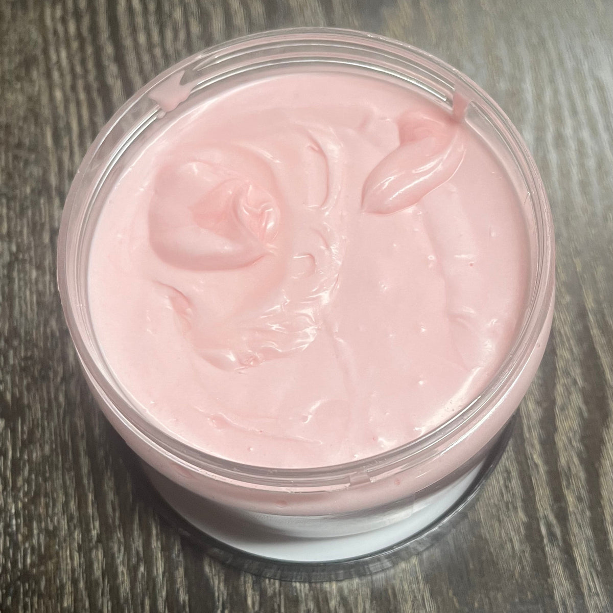 Jar of pink whipped body butter. You can slightly see a clear label on the front from this angle. 