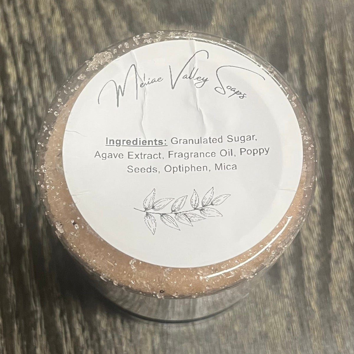 Jar of light brown sugar body scrub with a white ingredients label. 