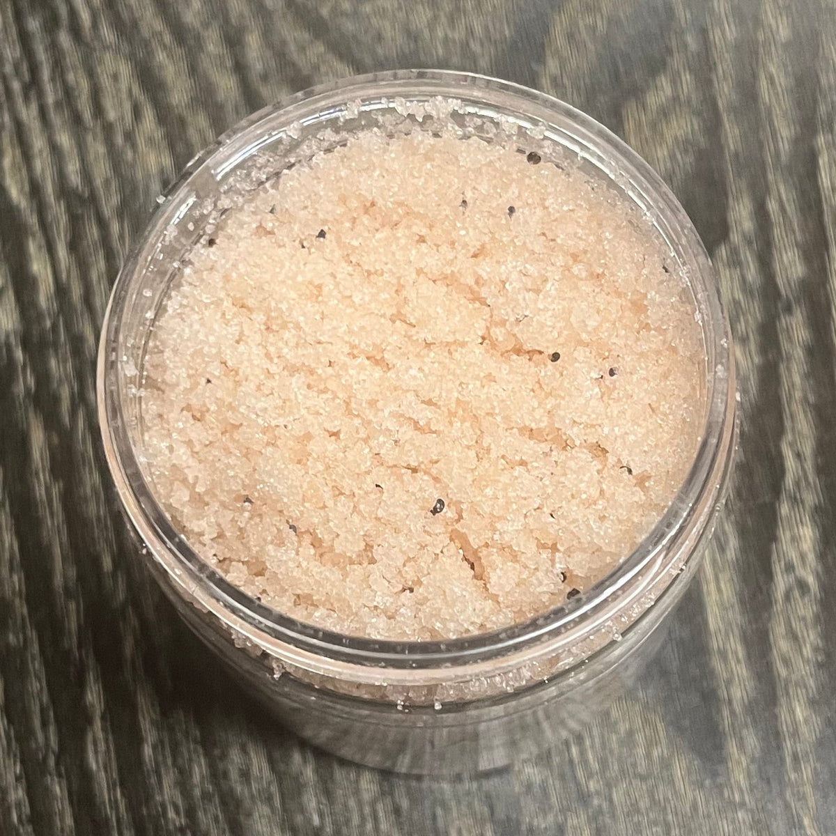 Jar of light brown sugar body scrub. You can slightly see a clear label on the front from this angle. 
