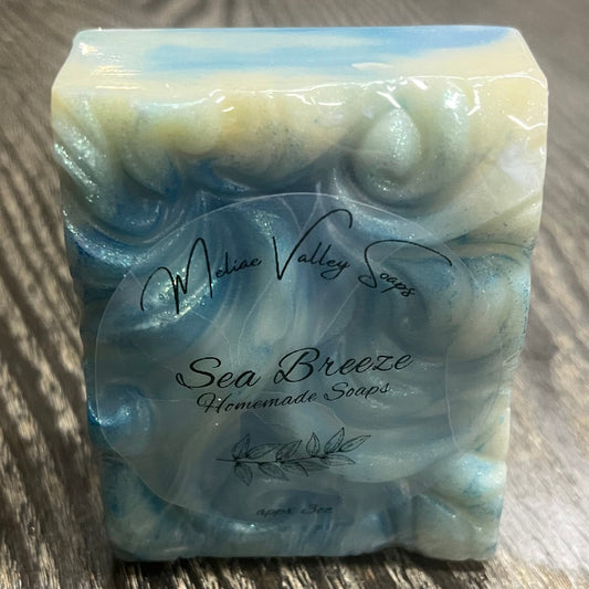 A bar of soap. It has a wavy texture and is swirled with different shades of blue and white. A clear label is on the front. 