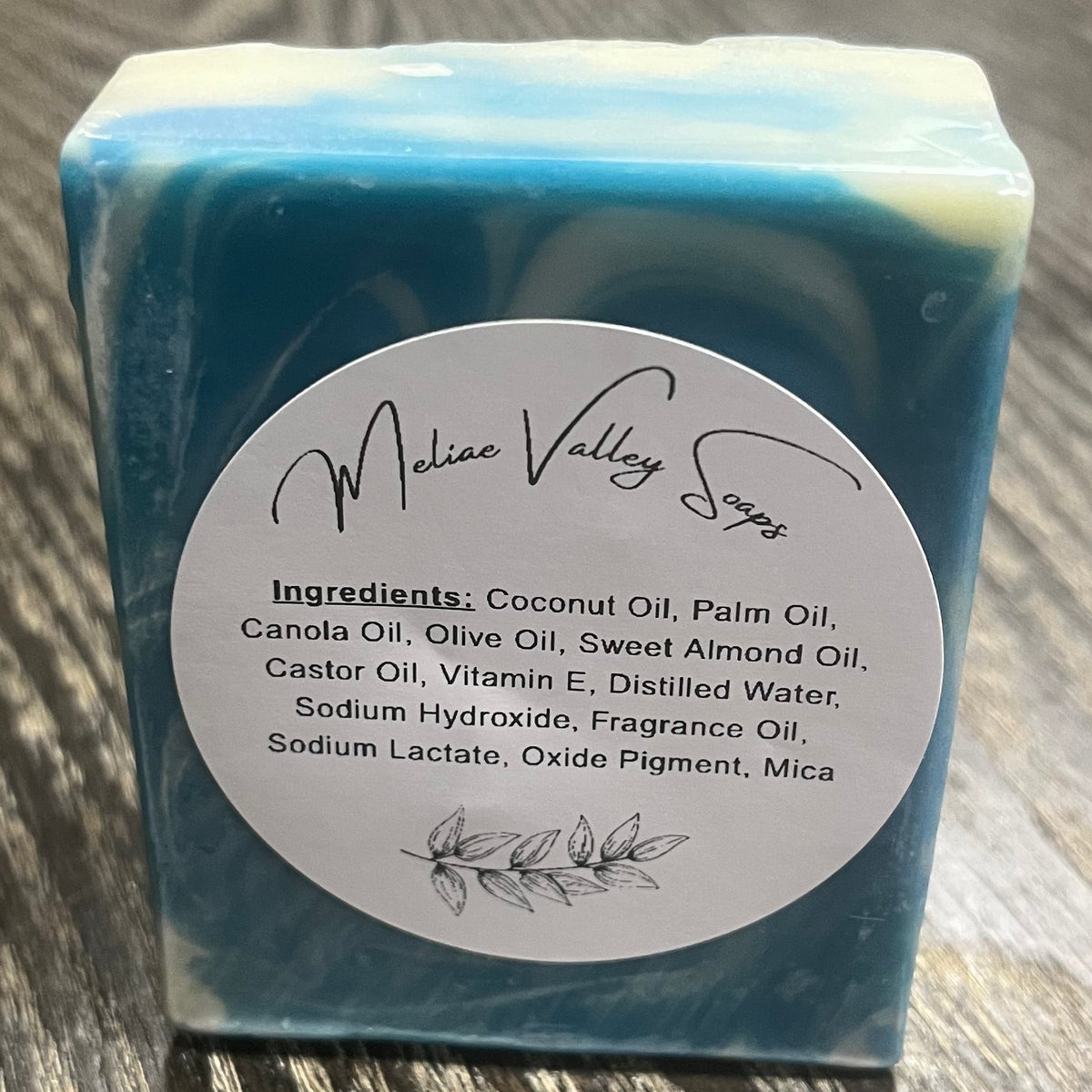A bar of soap. It has swirled with different shades of blue and white. A white ingredients label is on it. 