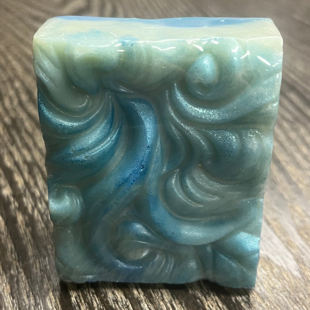 A bar of soap. It has a wavy texture and is swirled with different shades of blue and white. 