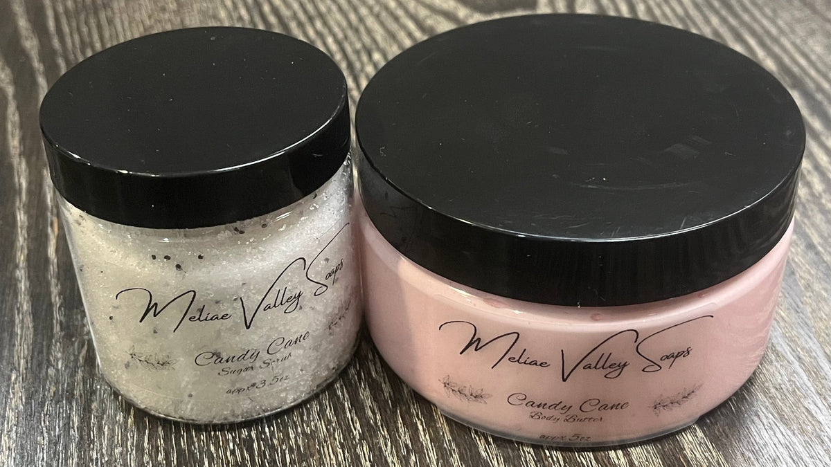 Two bottles next to each other. One has white whipped body butter; the other has a sugar scrub. Both have clear labels on the front. 