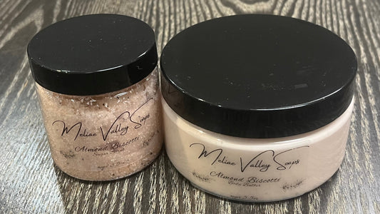 Two bottles next to each other. One has white whipped body butter; the other has a sugar scrub. Both have clear labels on the front. 