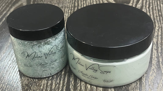 Two bottles next to each other. One has white whipped body butter; the other has a sugar scrub. Both have clear labels on the front. 