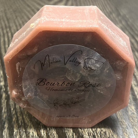 A dusty rose bar of soap. It has a clear label on the front. 